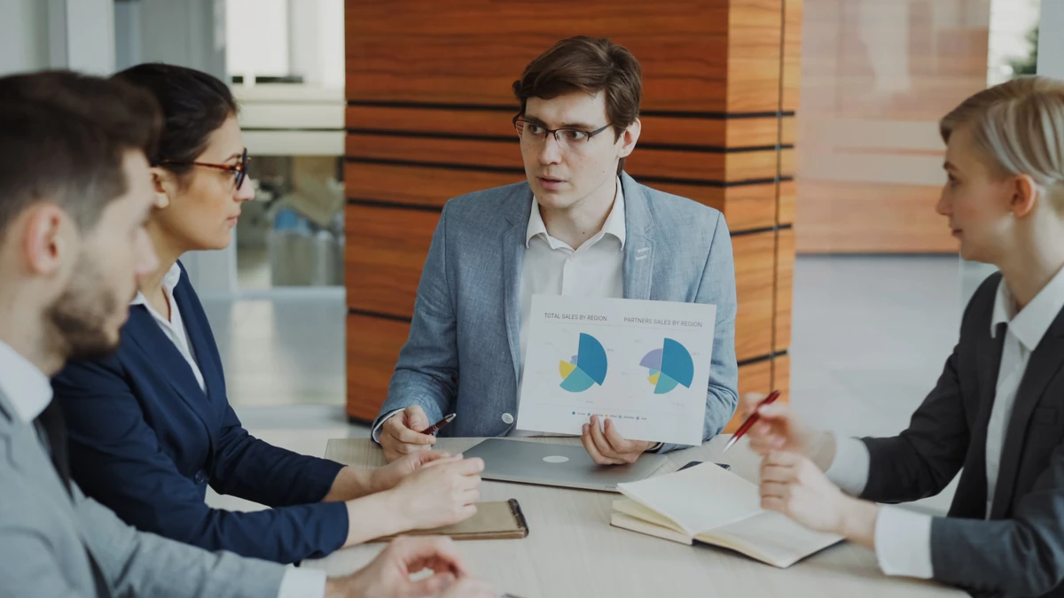 A business team discussing a presentation and printed charts in a meeting